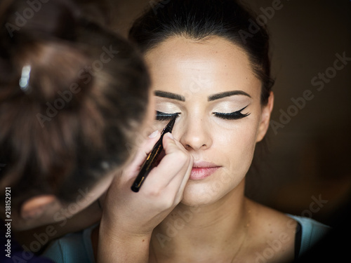 Make up artist doing professional make up of young woman.