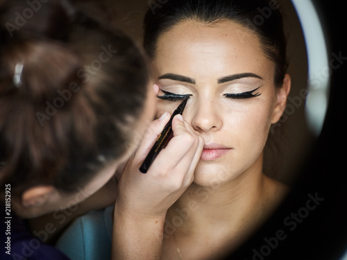 Make up artist doing professional make up of young woman. photo