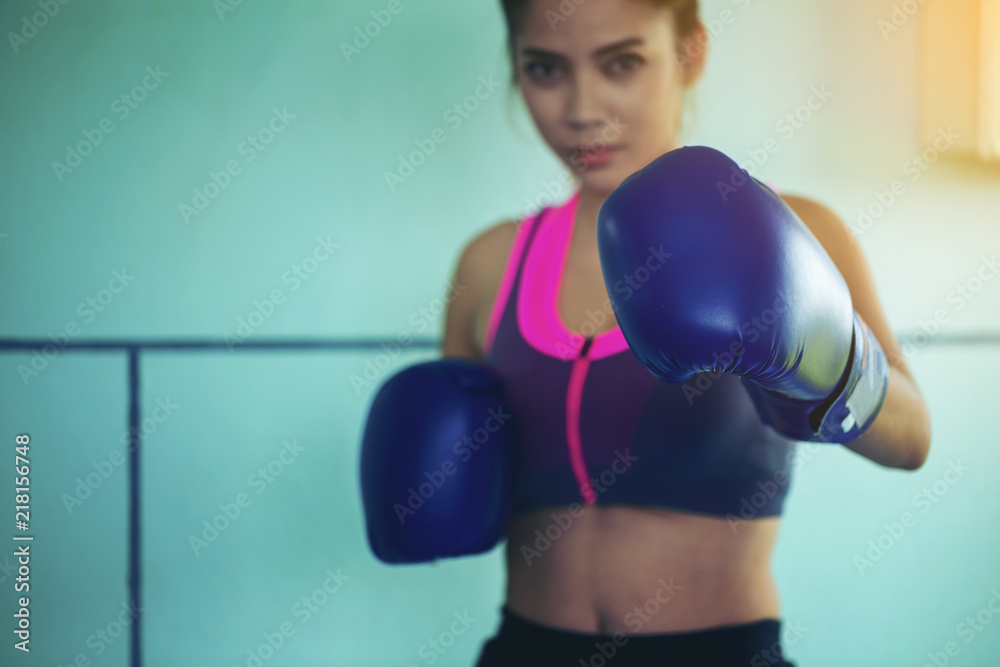 Beautiful girl with blue Boxing gloves looking at camera and ready to attack. Health Care Concept