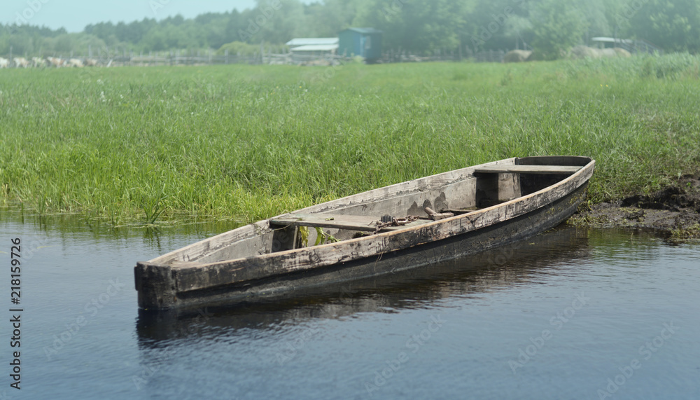 The old village wooden boat is moored at the river bank. Beautiful landscape.