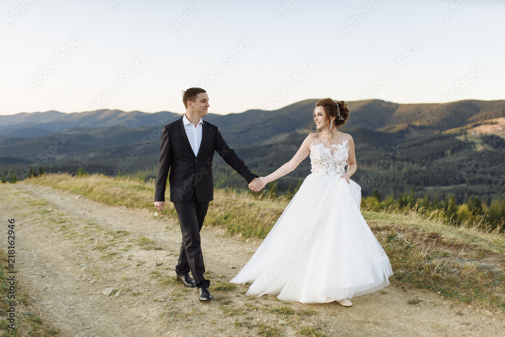 Wedding. Bridal bouquet. The bride's bouquet. The bride and groom running through the mountain slope, the bride holding a bouquet of white, pink and green colors with silk ribbons of pastel colors