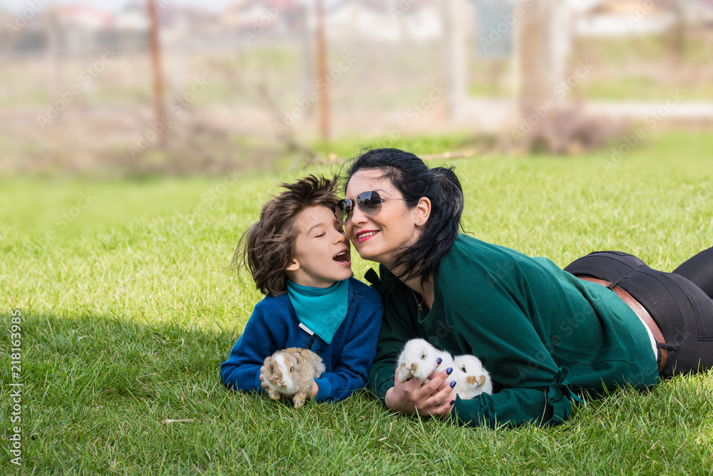 Lovely mother and son with bunnys in grass Lovely mother and son with bunnys in grass