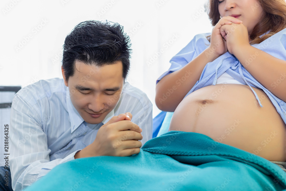 Handsome father and pregnant woman or mother are praying to the god and may god bless his baby and mother have good health and pregnant woman gives birth safety. Handsome daddy look nervous, excited Handsome father and pregnant woman or mother are praying to the god and may god bless his baby and mother have good health and pregnant woman gives birth safety. Handsome daddy look nervous, excited