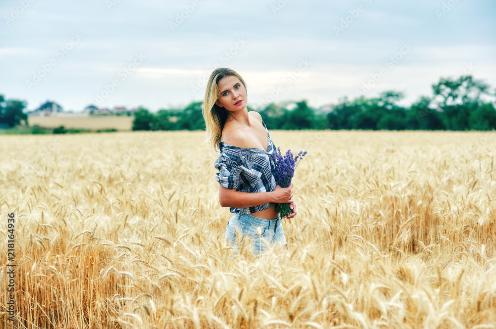 portrait of a young romantic woman on a walk in the countryside . Woman with a bouquet of lavender at a wheat field portrait of a young romantic woman on a walk in the countryside . Woman with a bouquet of lavender at a wheat field