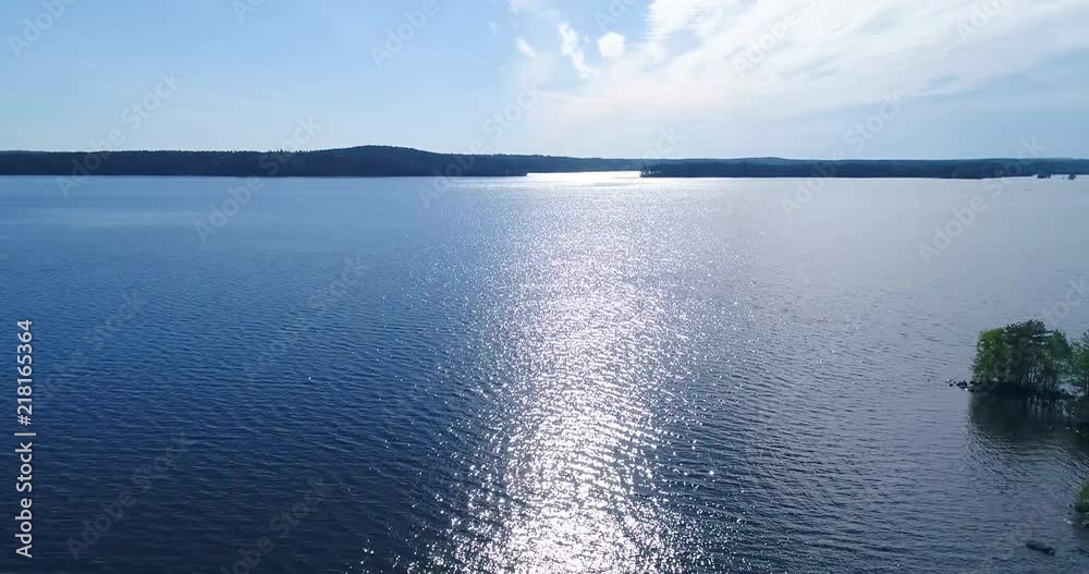 Aerial - Drone flying sideways above lake and water. Small islands with trees and rocks, clear and sunny summer day, calm waves and sun light reflections. Kangasala Finland Aerial - Drone flying sideways above lake and water. Small islands with trees and rocks, clear and sunny summer day, calm waves and sun light reflections. Kangasala Finland