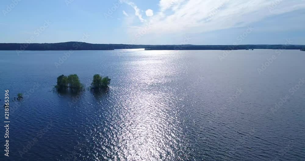 Aerial - Drone flying sideways above lake and water. Small islands with trees and rocks, clear and sunny summer day, calm waves and sun light reflections. Kangasala Finland Aerial - Drone flying sideways above lake and water. Small islands with trees and rocks, clear and sunny summer day, calm waves and sun light reflections. Kangasala Finland
