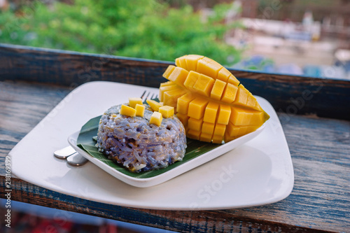 A beautiful healthy breakfast of sticky rice with fresh mango slices, an Asian breakfast in Laos. Sweet, sticky, purple rice with fresh mango slices. Asian cuisine. Healthy Eating photo