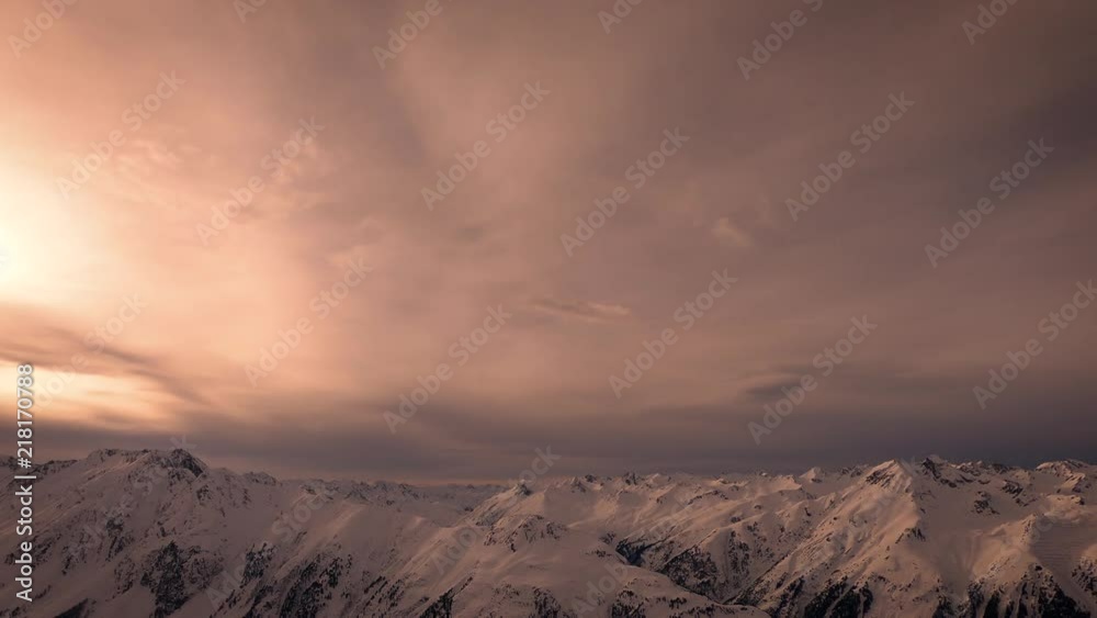 Snowy mountains and clouds time lapse with yellow orange and red warm sunlight and environment. Ischgl. Austria