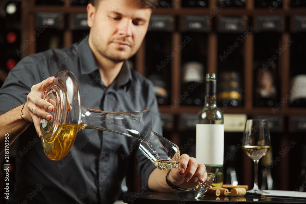 Sommelier pours white wine from decanter to the glass