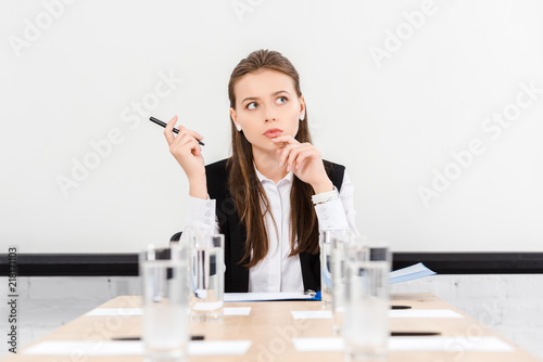 thoughtful young businesswoman sitting in conference hall at modern office