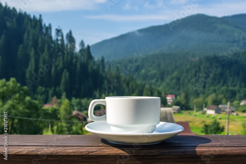 a cup of tea, coffee, standing on the porch of the hotel balcony, overlooking the mountains, in the early morning in the sunlight