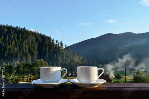 a cup of tea, coffee, standing on the porch of the hotel balcony, overlooking the mountains, in the early morning in the sunlight