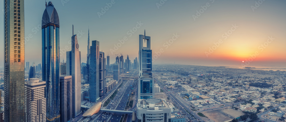 Fototapeta premium Skyscrapers and highways of a big modern city at sunset. Aerial panoramic view on downtown Dubai, United Arab Emirates.