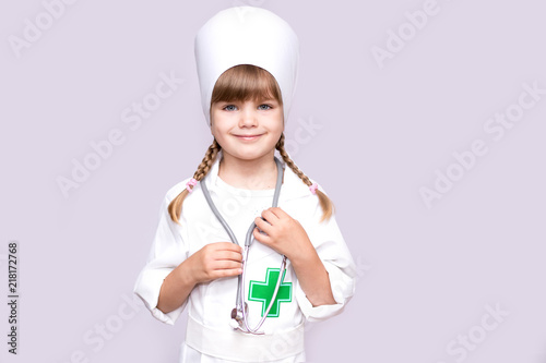 Smiling little girl in medical uniform looking at camera isolated on white