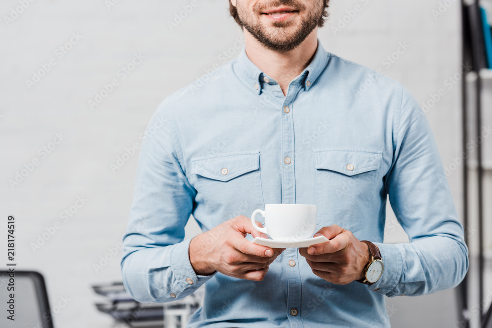 cropped shot of young businessman with cup of coffee at modern office cropped shot of young businessman with cup of coffee at modern office