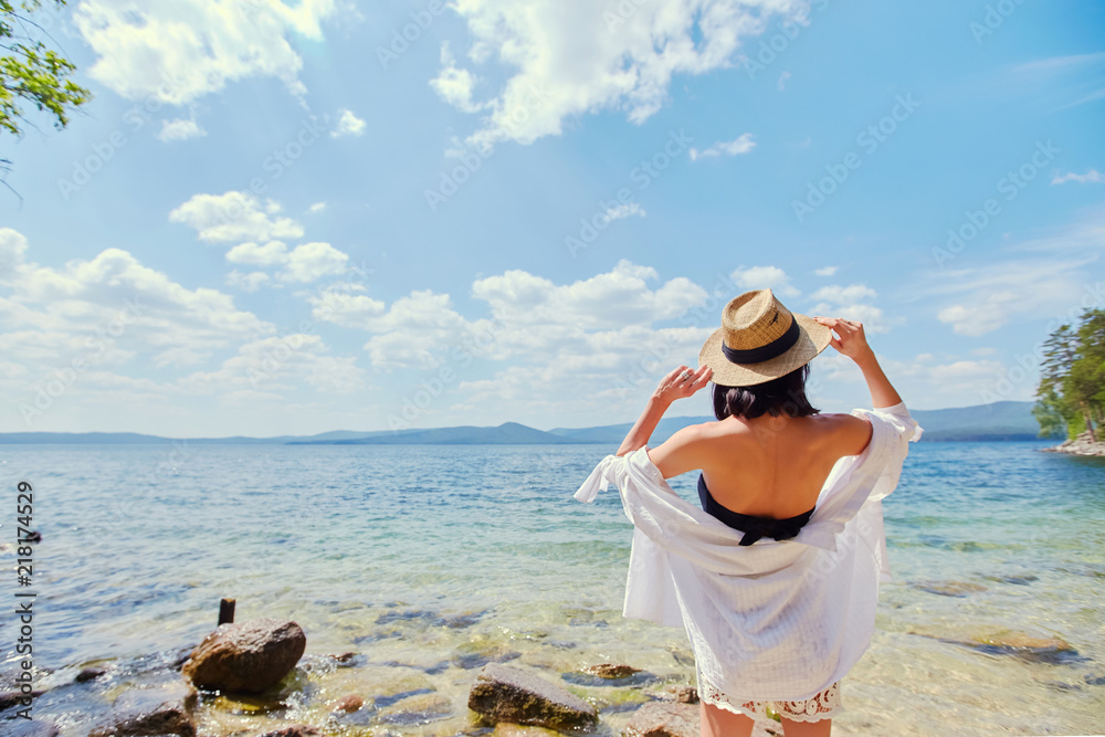 beautiful slender girl relaxing on the rocky beach of a large lake. beautiful slender girl relaxing on the rocky beach of a large lake.
