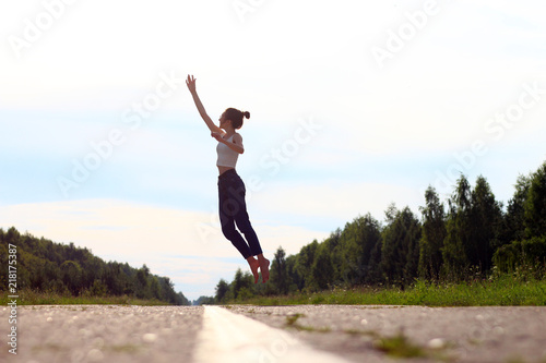 Happy young woman jumping having Fun Outdoors on the road. concept of freedom.