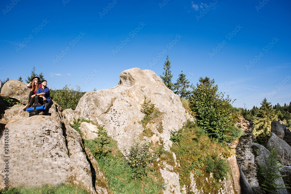 A hipster traveler couple sitting together on the rocks at the mountains