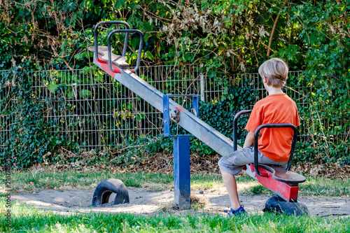 Valokuva Boy alone playing at the see-saw in the playground