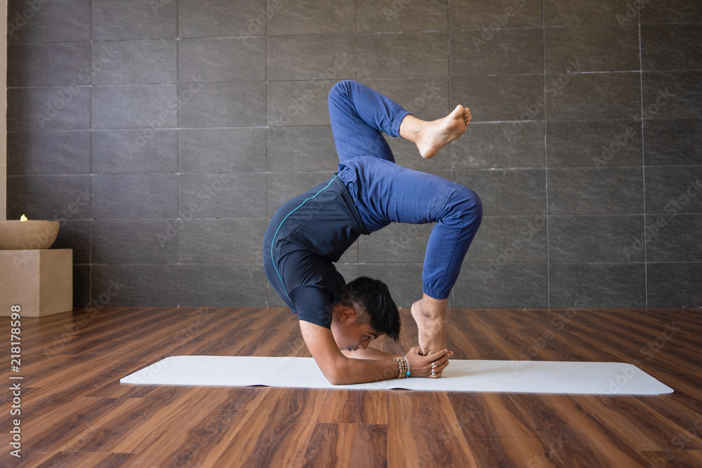 Yogi doing difficult hand stand yoga pose in gym. Man practicing advanced  yoga. Yogi concept. Stock Photo