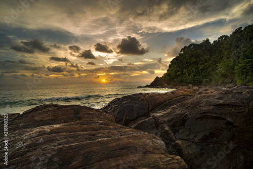 HDR processed dramatic sunset over sea beach on south islands in Thailand with a natural rock in the foreground.