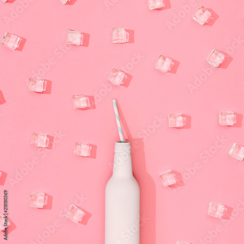 Ice cubes pattern with white painted bottle on pastel pink background. Minimal summer drink concept. Flat lay.