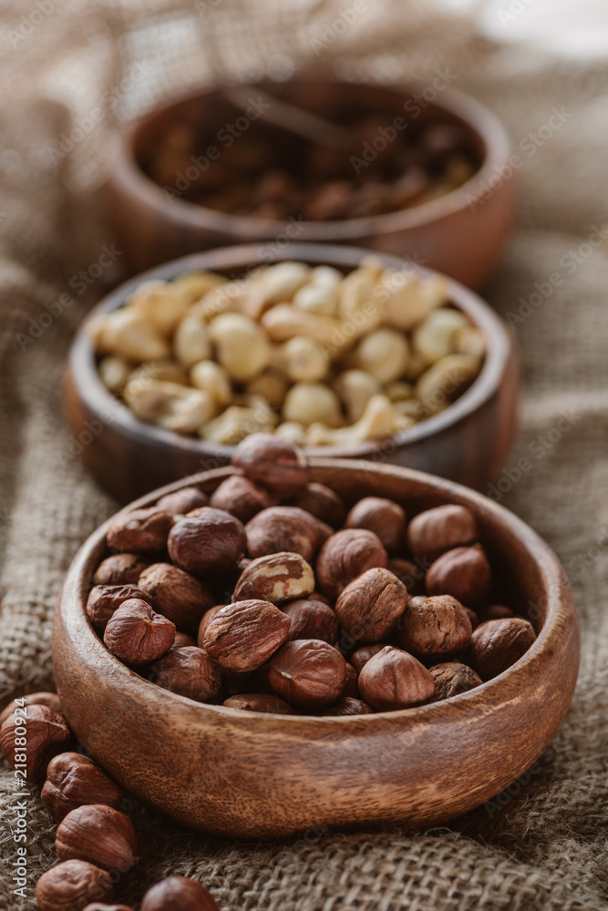 various nuts in wooden bowls on sackcloth various nuts in wooden bowls on sackcloth