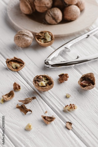 walnuts with metal nutcracker on white wooden surface