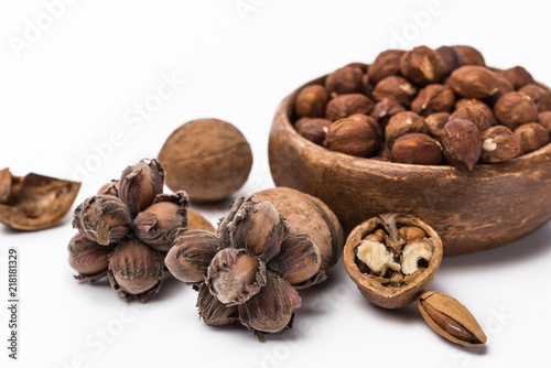 Obraz na płótnie hazelnuts in wooden bowl near walnuts and almond isolated on white background w salonie