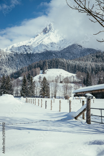 Winterlandschaft mit verschneiter Wiese, Holzzaun, Bergen und blauem Himmel © Patrick Daxenbichler