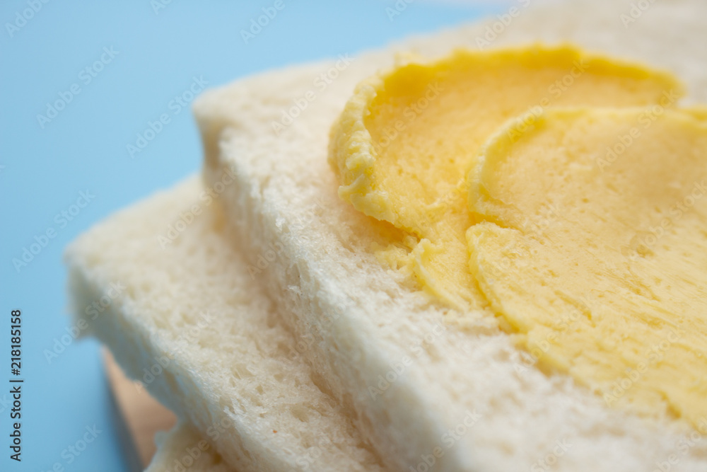 White no crust sandwich bread slices with sweet margarine on chopping board, on blue background White no crust sandwich bread slices with sweet margarine on chopping board, on blue background
