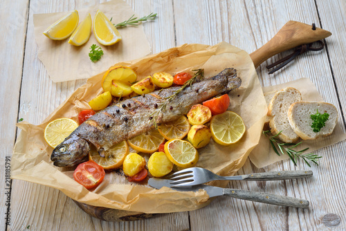 Gebackene Zitronen-Forelle mit leckerem Ofengemüse serviert auf Backpapier – Baked lemon trout with oven-roasted rosemary potatoes and tomatoes, served on baking paper