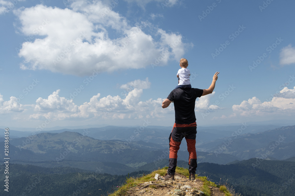 Father holding little girl on his shoulder while on top of the mountain. Sunny summer day. Freedom and parenting