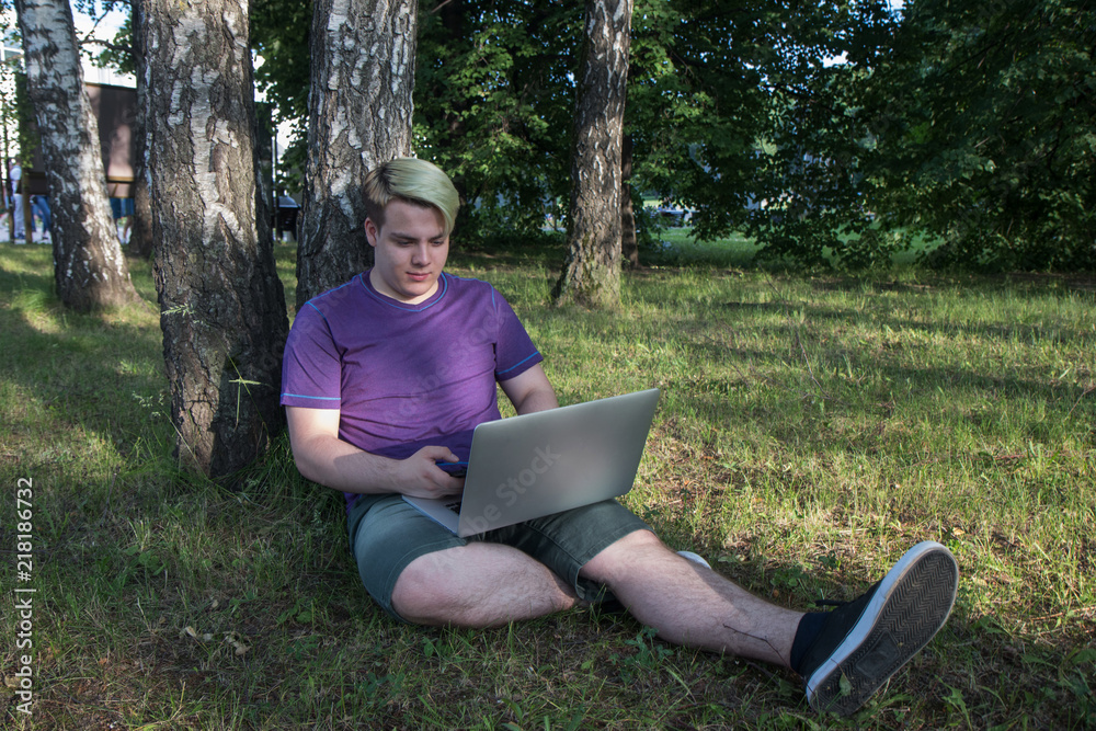 Hipster guy calling via cellphone and reading information from netbook Hipster guy calling via cellphone and reading information from netbook