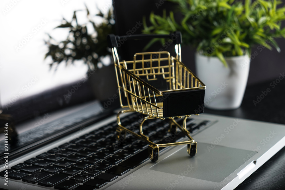 The concept of online shopping. Gold cart on a laptop. The concept of online shopping. Gold cart on a laptop.