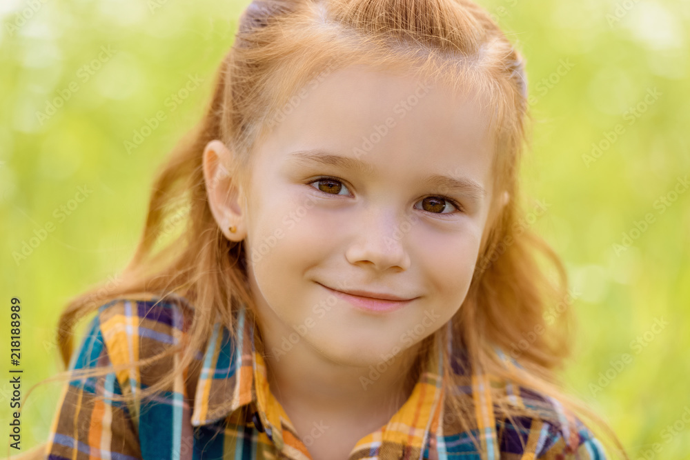portrait of adorable kid looking at camera with blurred green grass on background portrait of adorable kid looking at camera with blurred green grass on background