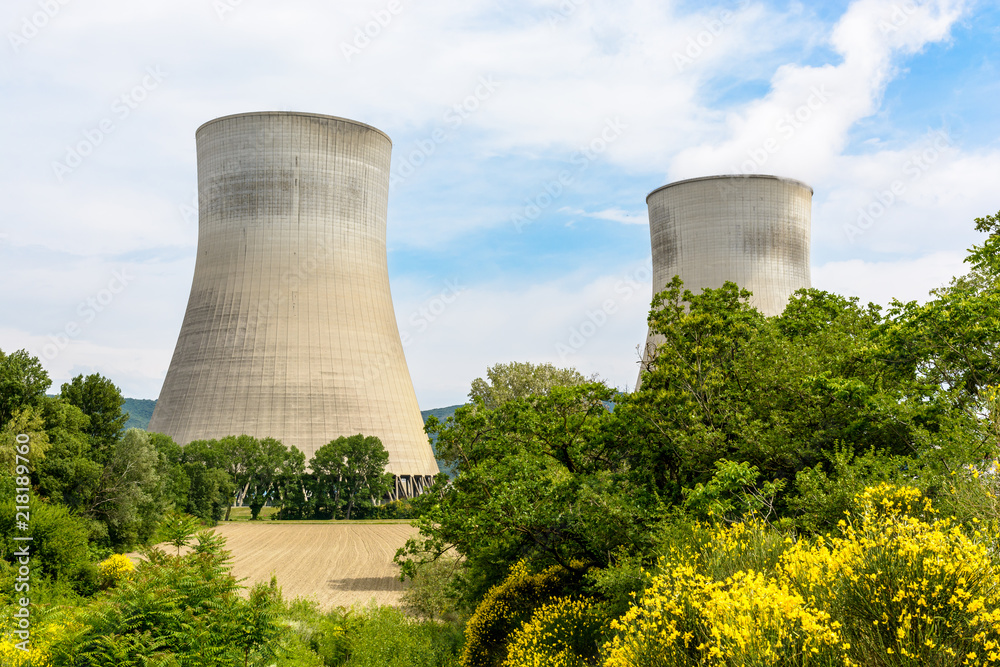 Two natural draft cooling towers of a nuclear power plant releasing clouds of water vapor in the middle of the countryside with a plowed field in the foreground. Two natural draft cooling towers of a nuclear power plant releasing clouds of water vapor in the middle of the countryside with a plowed field in the foreground.