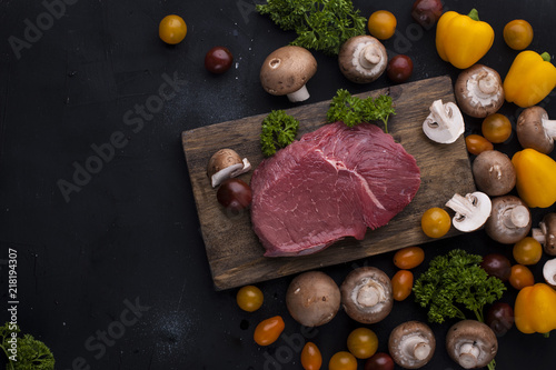 Steak meat on a black background. Beef and vegetables and mushrooms for cooking dinner. Free space for text. Top view