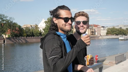 Two Boys Friends drinking Soda from metal Cans on a City Quay - Hot Summer Day