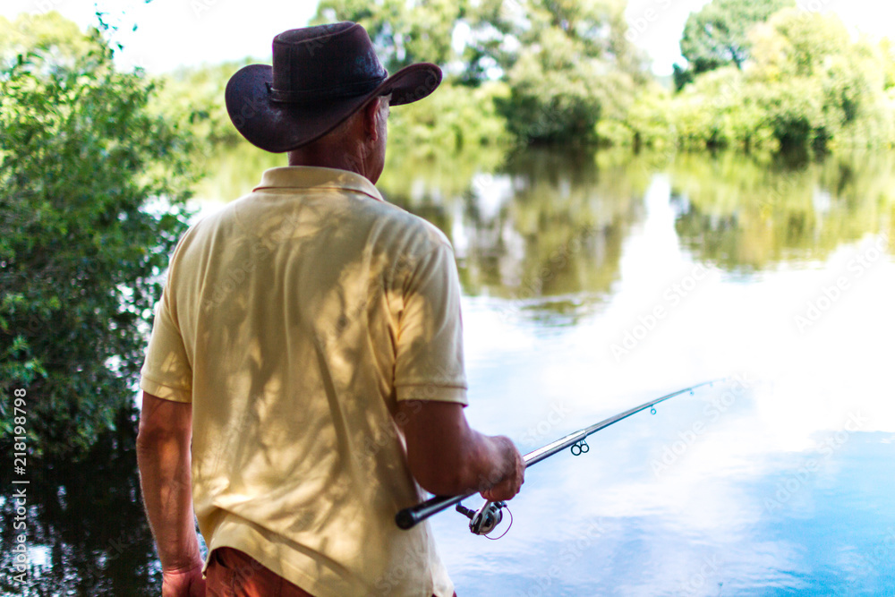 The fisherman is fishing on the shore of the lake. Fishing, recreation, hobbies. Fishery The fisherman is fishing on the shore of the lake. Fishing, recreation, hobbies. Fishery