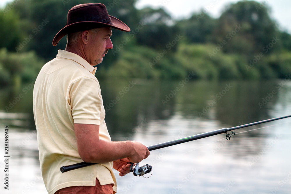 A fisherman in shorts and hat is fishing on the shore of the lake. Fishing A fisherman in shorts and hat is fishing on the shore of the lake. Fishing