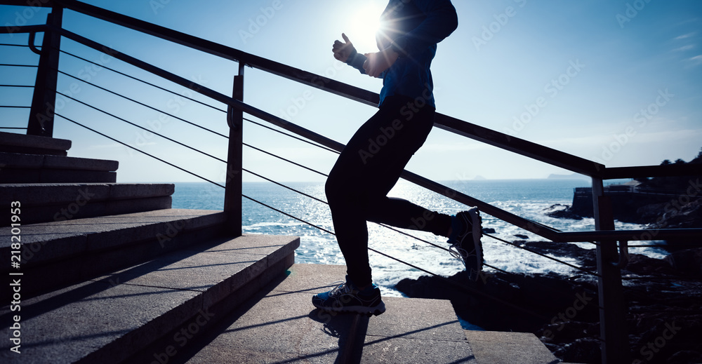 Sporty fitness female runner running up on seaside stairs