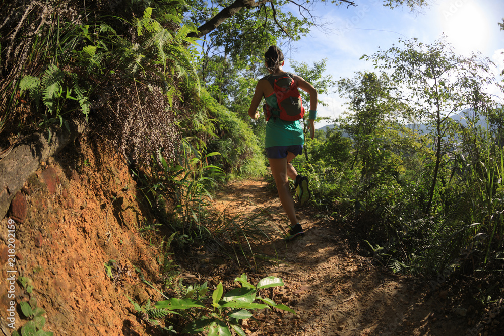 Determined woman trail runner running in morning forest