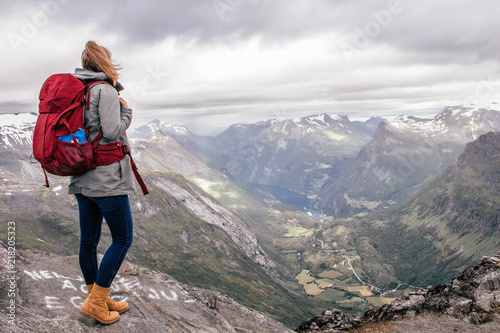 girl wandering on a mountain with a red backpack in Geiranger, Norway