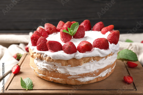 Delicious cake with strawberries on wooden board