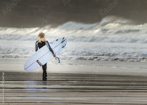 Blonde surfer walking on beach, Fistral, Newquay