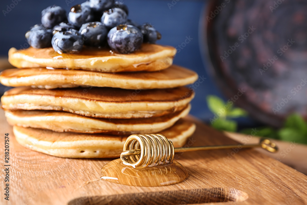 Tasty pancakes with blueberries and honey dipper on board, closeup Tasty pancakes with blueberries and honey dipper on board, closeup