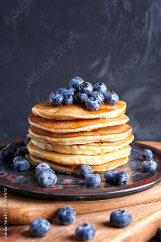 Plate with tasty pancakes and blueberries on board