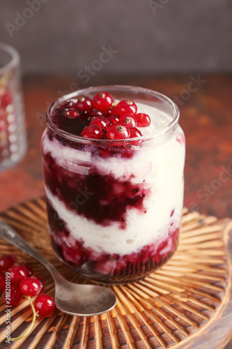 Glass jar with delicious rice pudding and currants on board
