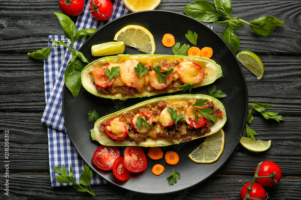 Plate with meat stuffed zucchini boats and vegetables on wooden table Plate with meat stuffed zucchini boats and vegetables on wooden table
